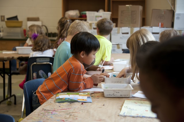 Niños coloreando hojas en el salon de clases.