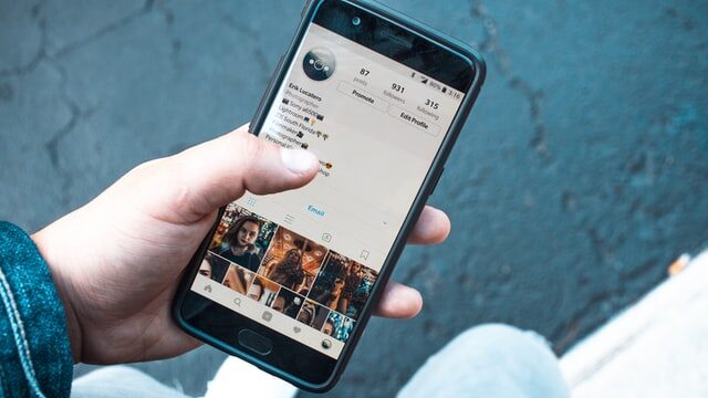 En la imagen se ve una mano sosteniendo un celular en el que se muestra una cuenta Instagram en la pantalla.